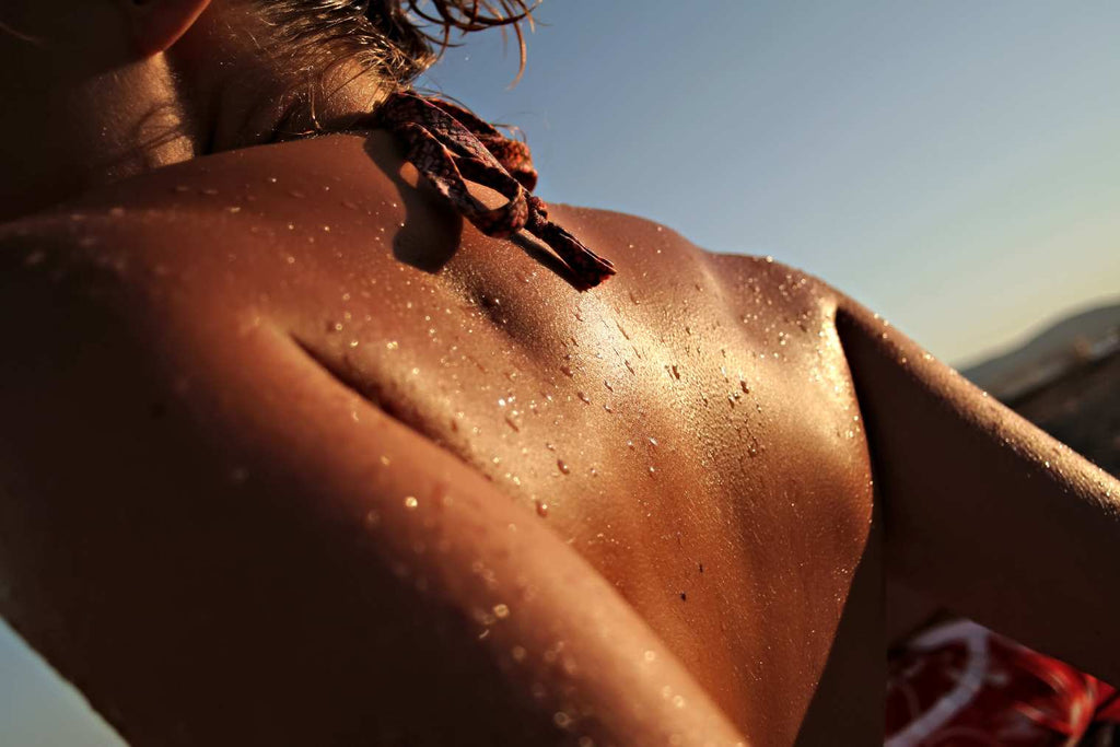 femme de dos à la plage qui bronze